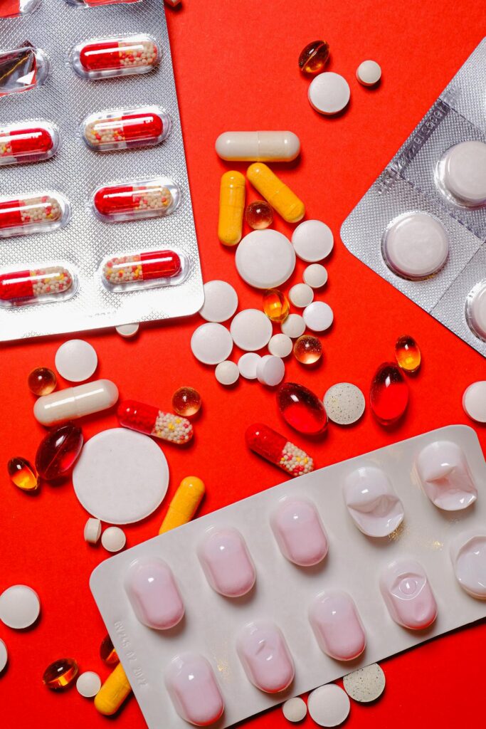 An assortment of colorful pills and capsules scattered on a vibrant red background